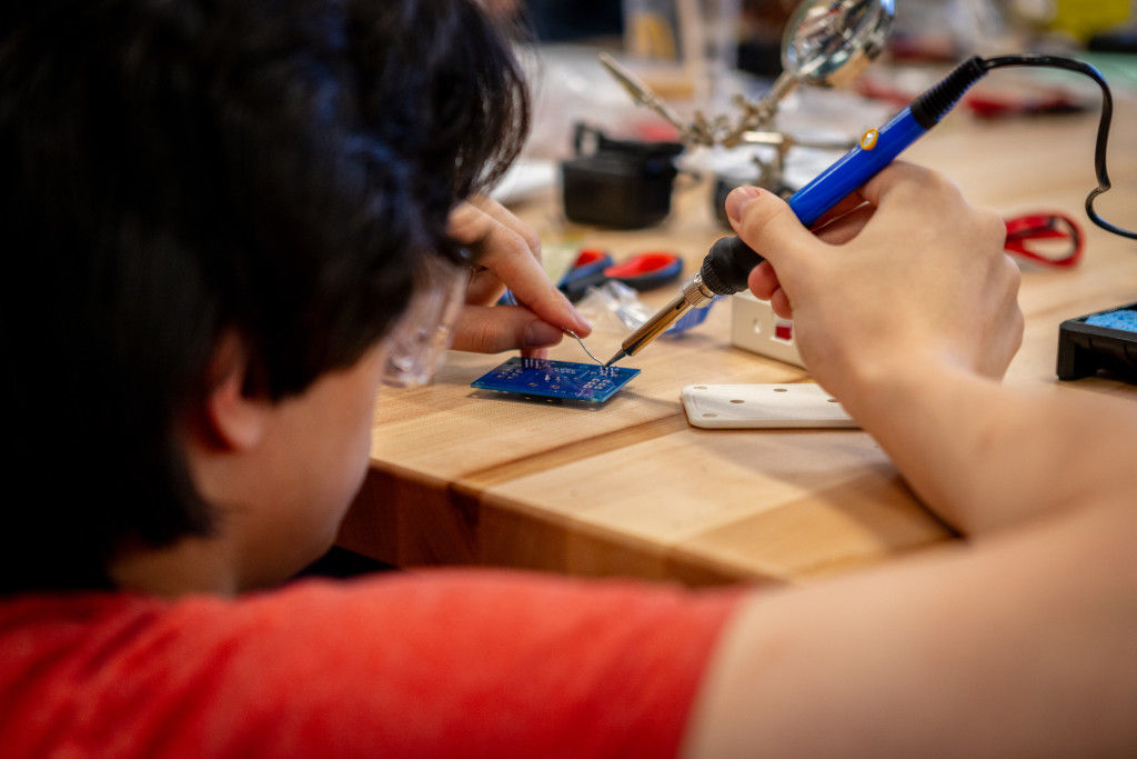 a male student using a solder on a circuit board