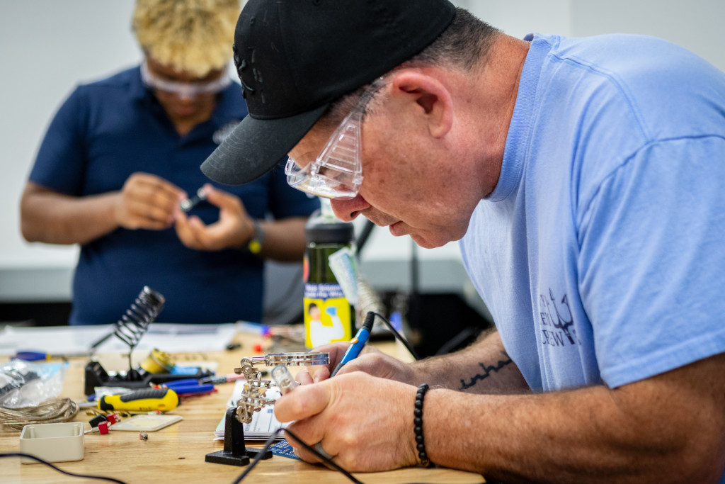 two male students conducting research with electronics with safety glasses on