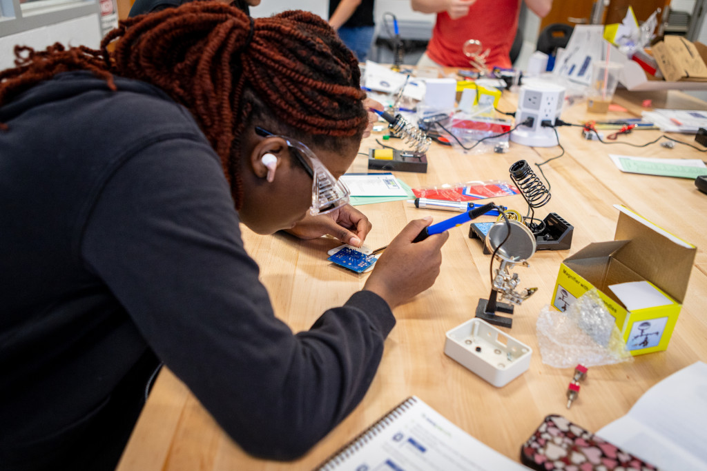 female student with welding tool with performing an experiment