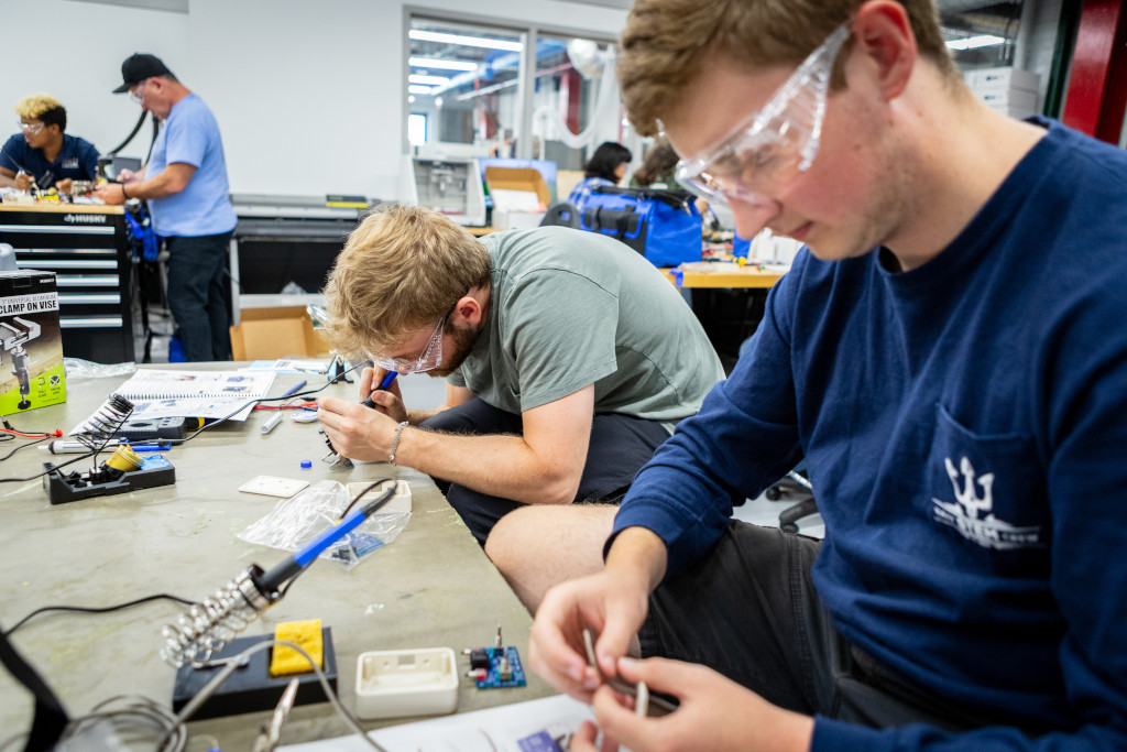 four male students conducting electronic research with safety glasses on