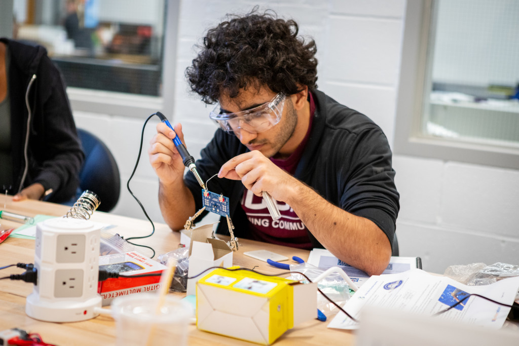 male student holding a welding tool at a workshop