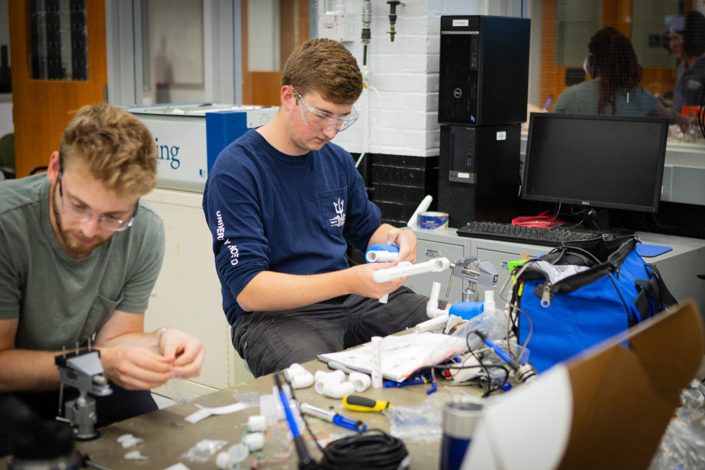 two male students performing experiements and work at a station