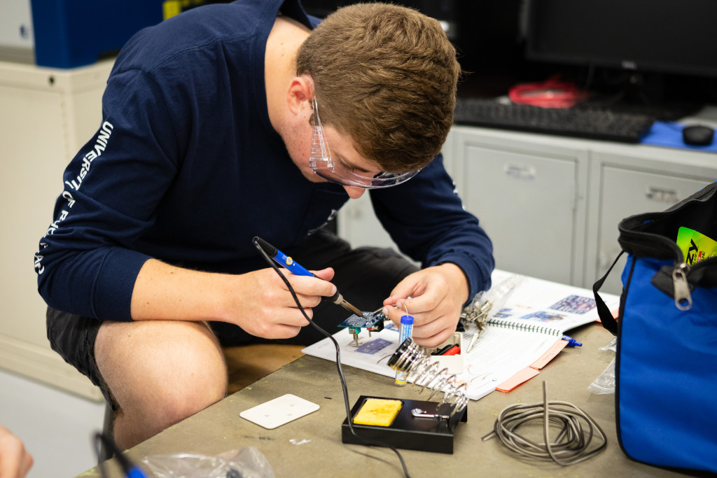 male student on motherboard experimenting